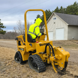 Technician operating a compact track trencher for professional underground pipeline and conduit installation