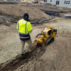 Technician operating a mini trencher for telecommunications and broadband infrastructure installation